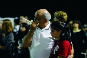 man in white shirt crying in crowd with arm around younger girl in red
